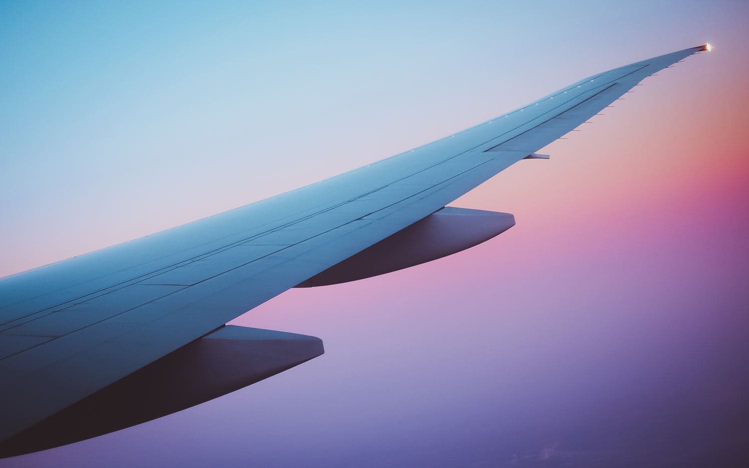 An aircraft wing reaching into a blue evening sky